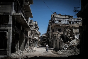 Um refugiado sírio caminha entre edifícios severamente danificados em Homs, na Síria, no dia 3 de junho de 2014.