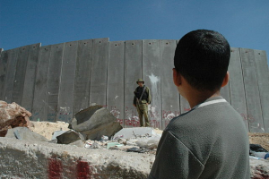 Menino palestino frente a um soldado sionista, no muro que o estado ultra-religioso construiu para reforçar o apartheid contra o povo palestino